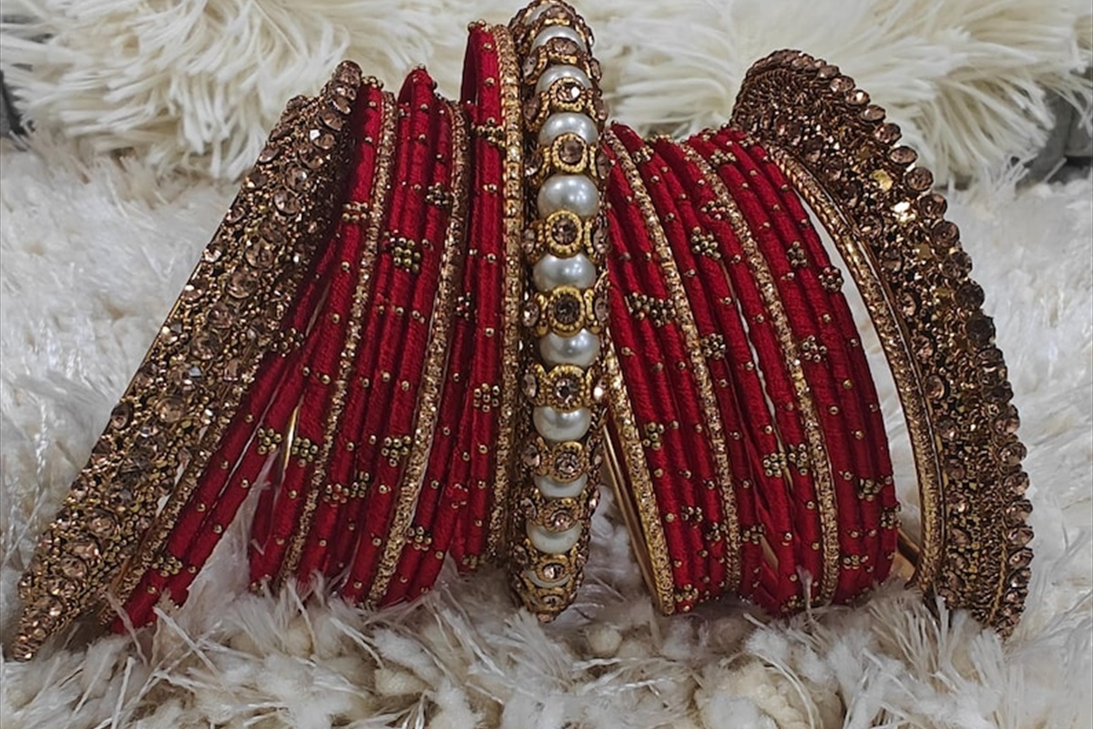 Assorted red and gold bangles arranged on crimson silk